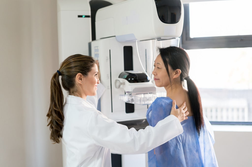 Female radiologist positioning patient for a mammogram screening to detect breast cancer
